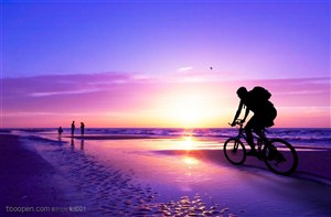 朝阳下海滩边骑车的人高清图片