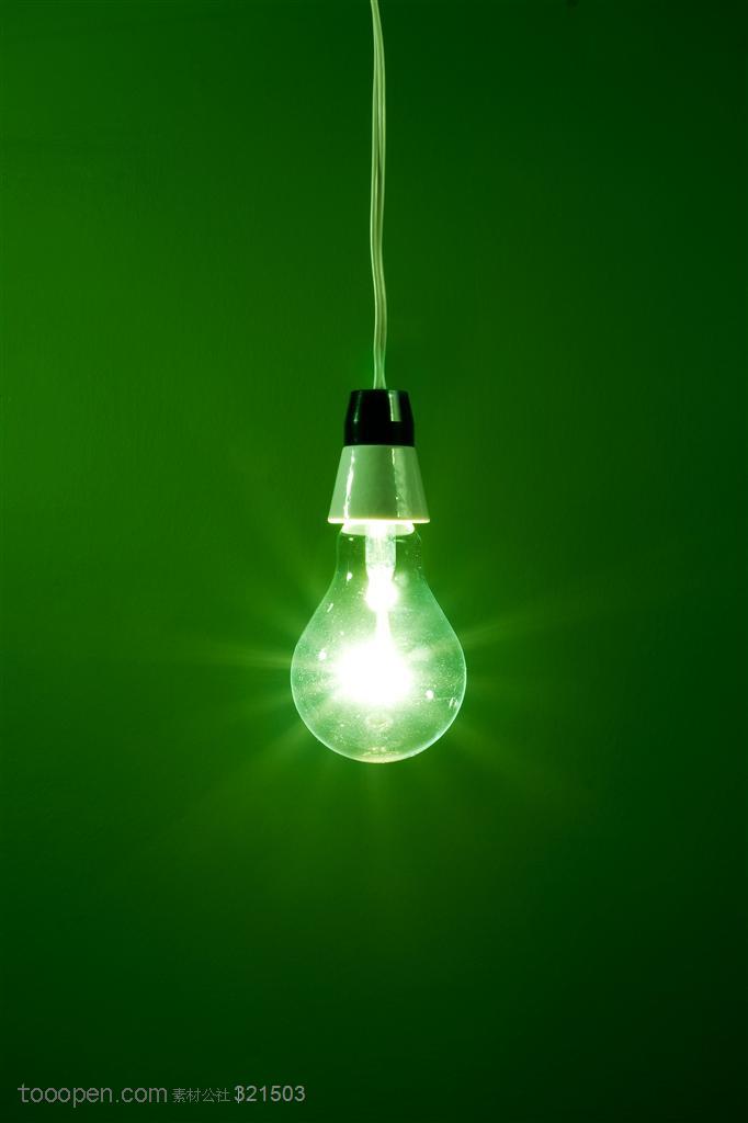 创意灯泡-绿色背景前亮着的灯泡